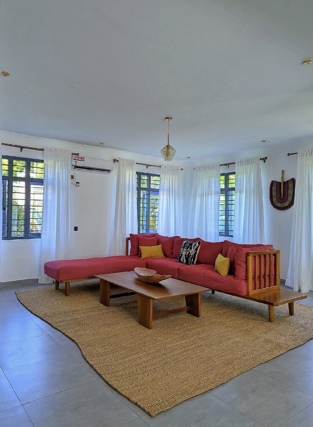 Mila Bustani's living room, red sectional on a jute rug